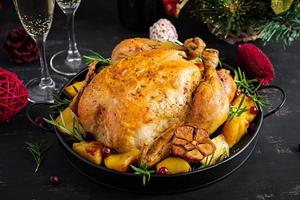 Baked turkey or chicken. The Christmas table is served with a turkey, decorated with bright tinsel. Fried chicken, table setting. Christmas dinner. photo