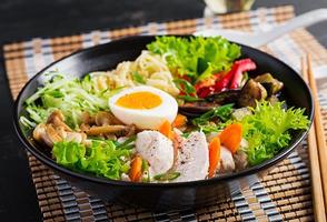 Japanese ramen soup with chicken, egg, shimeji mushrooms and eggplants on dark wooden background. Chanko nabe, sumo soup. photo