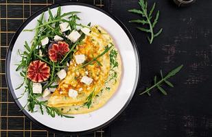 Omelette with feta cheese, parsley and salad with figs, arugula on white plate. Frittata - italian omelet. Top view. Flat lay. photo