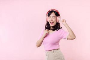 Smile pretty model person listen music song and enjoy dance with wireless headphone online audio radio sound. Positive fun exited joyful youth female woman sing on pink isolated background studio