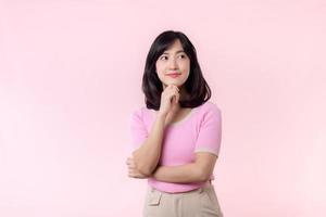Portrait beautiful young asian woman thoughtful thinking an idea isolated on pink pastel background. Teenage female person pretty smile with thinking gesture concept. photo