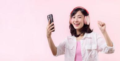 People emotions, lifestyle leisure and beauty concept. Carefree good-looking asian woman dancing relaxed with smartphone, listening music in wireless headphones