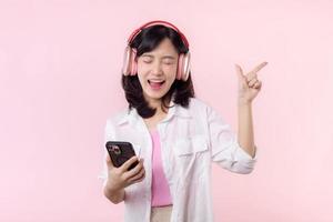 People emotions, lifestyle leisure and beauty concept. Carefree good-looking asian woman close eyes and dancing relaxed with smartphone, listening music in wireless headphones photo