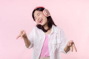 Smile pretty model person posing Y2K, listen music song and enjoy dance with headphone online audio radio sound. Positive fun exited joyful youth female woman sing on pink isolated background studio photo
