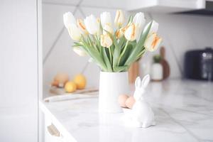 Pascua de Resurrección mesa ajuste con tulipanes, Pascua de Resurrección conejitos, y huevos con dorado patrones en el blanco estilo escandinavo cocina antecedentes. hermosa minimalista diseño para saludo tarjeta