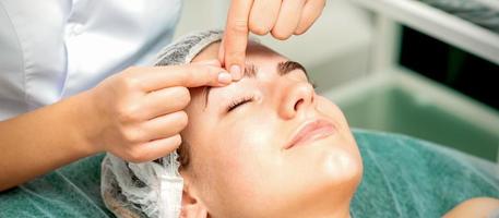 Beautician make massage on eyebrow photo