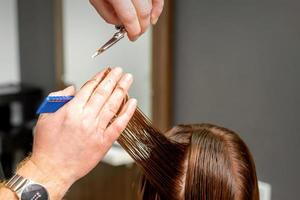 Hairdresser's hands cuts female hair photo