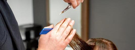 Hairdresser's hands cuts female hair photo