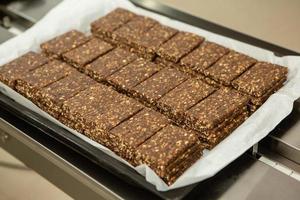 Assortment of cereal or protein bars that leave the assembly line at the factory. Healthy pre or post workout snacks with fruits, nuts and berries. photo