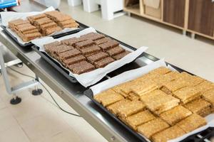 Assortment of cereal or protein bars that leave the assembly line at the factory. Healthy pre or post workout snacks with fruits, nuts and berries. photo