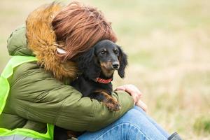 Woman hugs her cute dog on the grass. photo