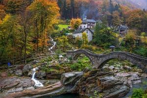 un pequeño pueblo con un Roca puente en otoño lluvioso clima