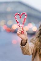 A candy cane girl in the shape of a heart against the background of blurred Christmas city lights. photo