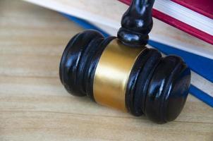 Close up of Lawyer's gavel on wooden table with stack of books background. Copy space and law concept photo