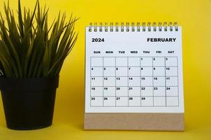 February 2024 month calendar with table plant on yellow cover background. Monthly calendar concept. photo