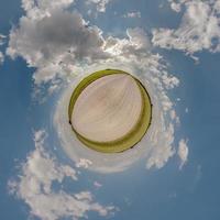 tiny planet in blue overcast evening sky with beautiful clouds with transformation of spherical panorama 360 degrees. Spherical abstract aerial view. Curvature of space. photo