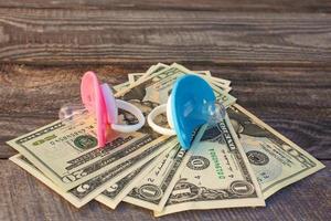 Blue and pink pacifiers on the background of money. photo