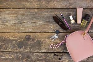 Things from open lady purse. Cosmetics and women's accessories fell out of handbag on old wooden background. Top view. photo