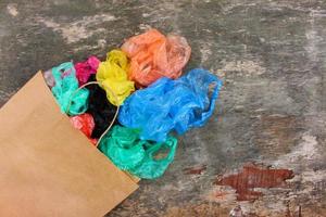 From paper bag poured plastic bags on old wooden background. Top view. Flat lay. photo