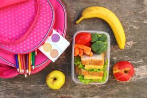 Sandwiches, fruits and vegetables in food box, backpack on old wooden background. Top view. Flat lay. photo