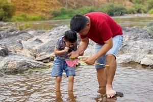 asiático padre y chico son teniendo divertido explorador el acuático ecosistema. el concepto de aprendizaje fuera de el aula, hogar escuela, natural aprendizaje recursos. suave y selectivo enfocar. foto