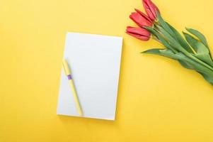 Top view of yellow desk with blank notebooks mockup with pencil and tulips. notebook photo