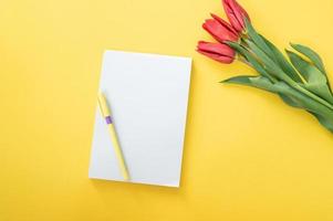 parte superior ver de amarillo escritorio con blanco cuadernos Bosquejo con lápiz y tulipanes cuaderno foto