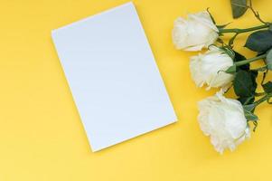 Top view of a yellow table with a mockup of empty notebooks with a bouquet of roses. Place for text photo