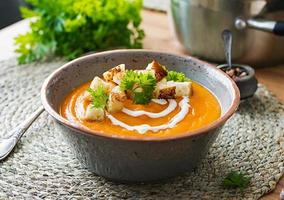 Pumpkin soup in a bowl served with parsley and croutons. Vegan soup. Thanksgiving day food. Halloween meal. photo