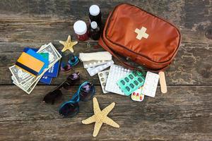 Summer women's beach accessories for your sea holiday and first aid kit on old wooden background. Concept of medication required in journey. Top view. Flat lay. photo