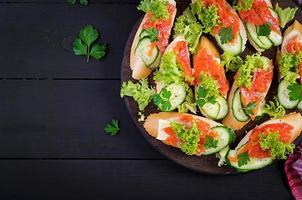 Tapas.  Salted Salmon, butter and cucumber toast sandwiches on wooden board. Top view photo