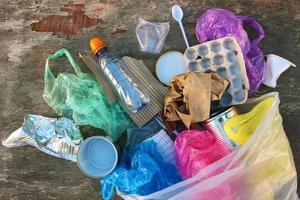 Garbage bag with different trash on wooden background. Top view. Flat lay. photo