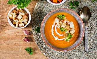 Pumpkin soup in a bowl served with parsley and croutons. Vegan soup. Thanksgiving day food. Halloween meal. Top view photo
