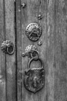 Black and white of an old wooden door with a big vintage padlock. True retro style.Close up photo