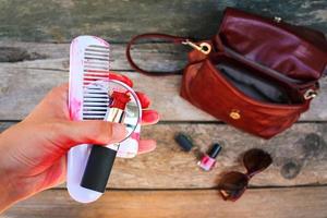 Broken red lipstick, mirror, comb in women hand. photo