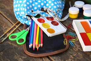 School supplies fall out of backpack on old wooden background. photo