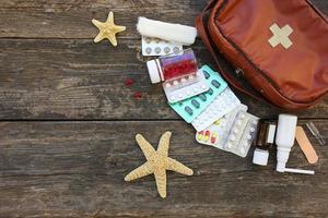 First aid kit on old wooden background. Concept of medication required in journey. Top view. Flat lay. photo