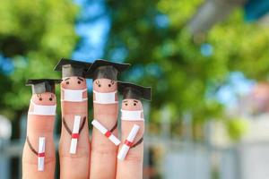 Fingers art of students in medical mask from COVID-2019. Graduates holding their diploma after graduation. photo