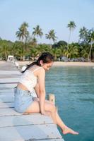 Asian young woman on a wooden bridge at the sea in the tropics on a long vacation travel concept photo