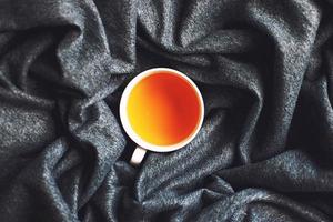 cup of hot tea on a gray soft plaid close. Top view photo