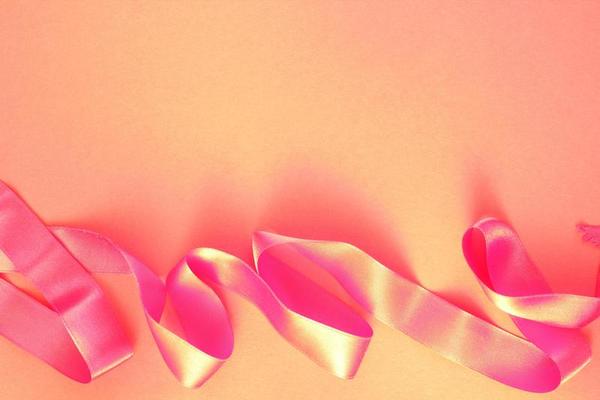 Curved wavy silk satin red ribbon on pink background with copy space for text. Holiday, celebration, anniversary, birthday gift decoration concept. Idea for greeting card, sale banner