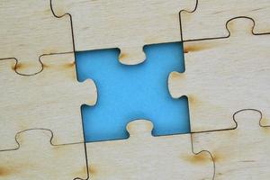 Incomplete and absence wooden puzzle piece with blue backdrop. Missing piece. Mental health concept. Symbol of problem solving. Business creative solution. Communication idea. Hobby, play, fun game photo