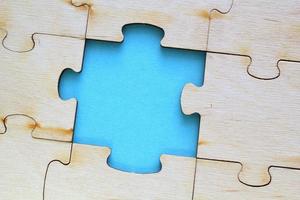 Incomplete and absence wooden puzzle piece with blue backdrop. Missing piece. Mental health concept. Symbol of problem solving. Business creative solution. Communication idea. Hobby, play, fun game photo