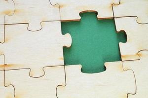 Incomplete and absence wooden puzzle piece with green backdrop. Missing piece. Mental health concept. Symbol of problem solving. Business creative solution. Communication idea. Hobby, play, fun game photo