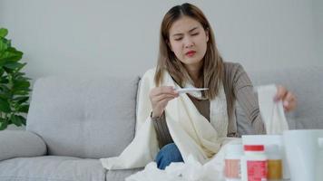 joven asiático mujer teniendo alto fiebre mientras comprobación cuerpo temperatura, hembra estornudos y líquido nariz con estacional influenza, tomando medicamento, virus, coronavirus, enfermedad, respiratorio, alérgico video