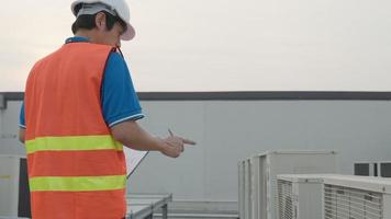 Asian maintenance engineer works on the roof of factory. contractor inspect compressor system and plans installation of air condition systems in construction. Checklist, inspector, control video