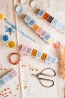 Items for beading - boxes with beads, thread and scissors on the table. Development of creative skills and fine motor skills for children. Top and vertical view. photo