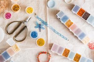 Items for beading - boxes with beads, thread and scissors on the table. Development of creative skills and fine motor skills for children. Top view. photo