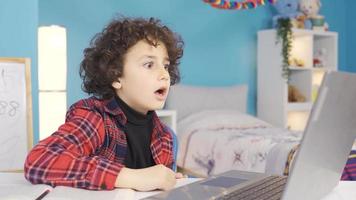 Junge überrascht durch Was er gesehen. das männlich Schüler suchen beim das Laptop ist überrascht und glücklich durch Was er sieht auf das Bildschirm. video