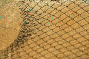 Broken Chain Fence Shadow on Concrete Ground. photo